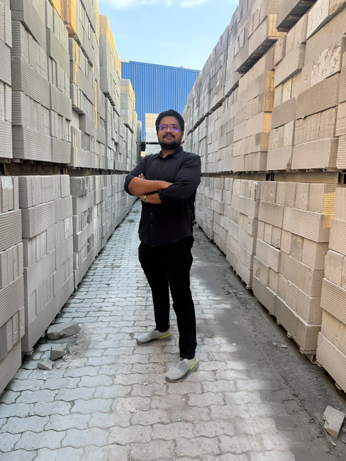 Mohammad Afridi standing between stacks of AAC blocks at a manufacturing facility